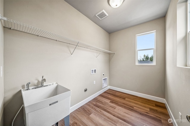 clothes washing area featuring sink, hardwood / wood-style flooring, hookup for a gas dryer, electric dryer hookup, and washer hookup