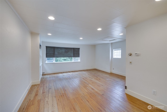 empty room with light hardwood / wood-style floors and crown molding