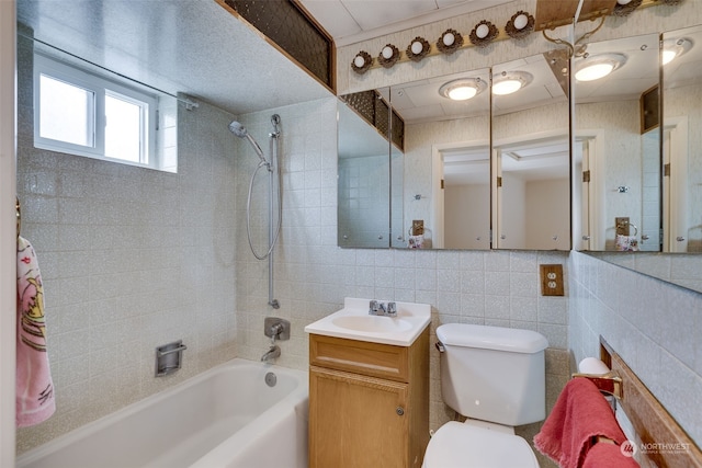 full bathroom featuring oversized vanity, tile walls, toilet, and tiled shower / bath combo