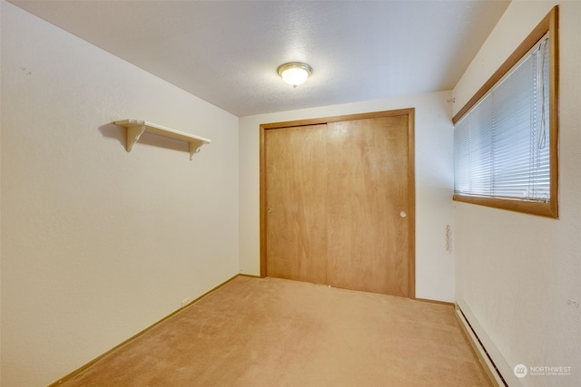 unfurnished bedroom with a closet, carpet floors, and a baseboard radiator