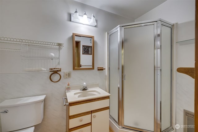 bathroom featuring vanity with extensive cabinet space, a shower with shower door, toilet, and tile walls