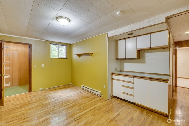 basement featuring a baseboard heating unit and light hardwood / wood-style floors