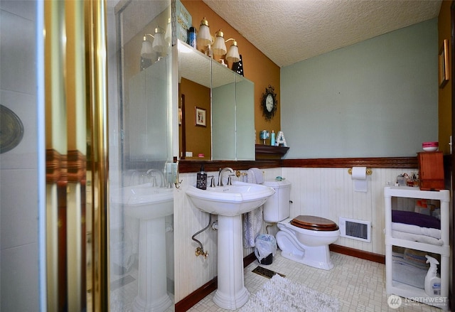 723 Gish Rd, Onalaska, WA 98570 - bathroom featuring toilet, a wainscoted wall, tile patterned floors, a shower stall, and a textured ceiling