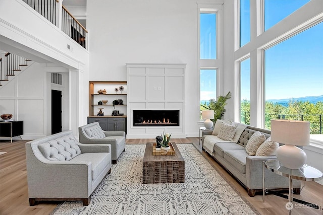 living room with a towering ceiling and light hardwood / wood-style flooring