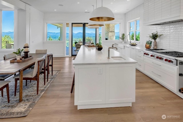 kitchen featuring light wood-type flooring, sink, pendant lighting, a mountain view, and stainless steel gas stovetop