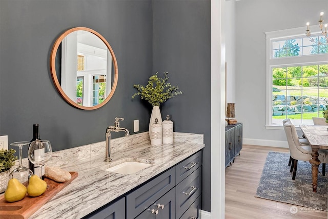 interior space with gray cabinetry, light stone countertops, sink, and light hardwood / wood-style flooring