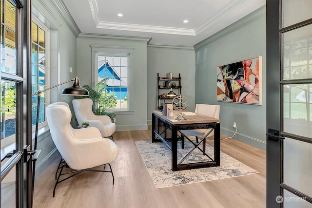 office space with light wood-type flooring, a tray ceiling, and crown molding