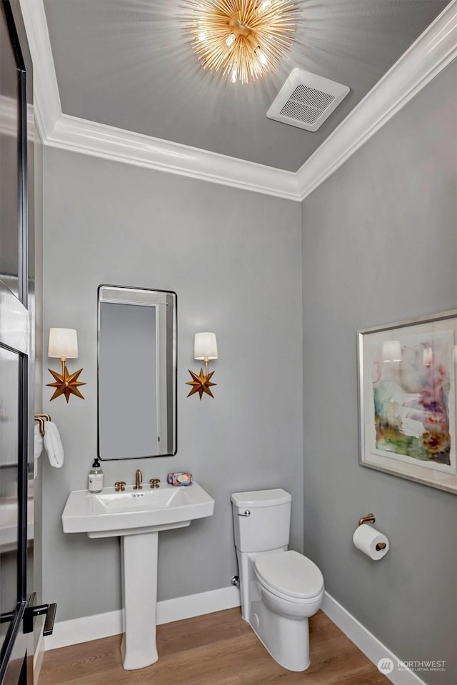 bathroom featuring hardwood / wood-style floors, toilet, and crown molding