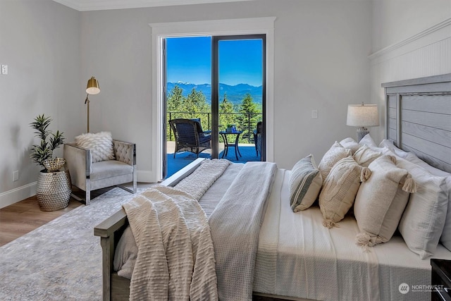 bedroom with access to outside, a mountain view, and wood-type flooring