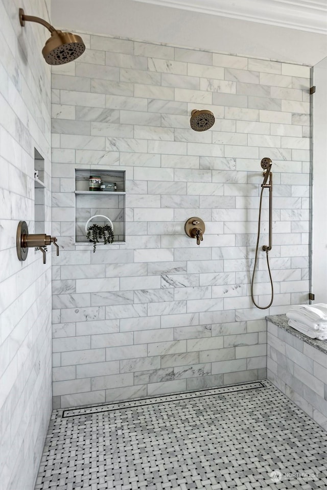 bathroom with ornamental molding and tiled shower