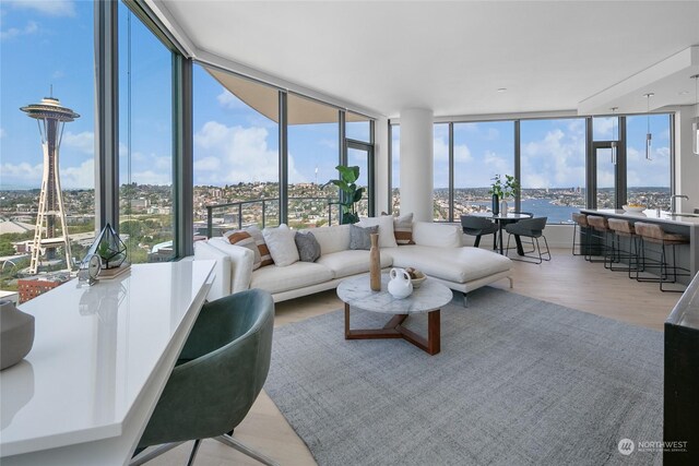 living room with light hardwood / wood-style flooring, a water view, a healthy amount of sunlight, and expansive windows