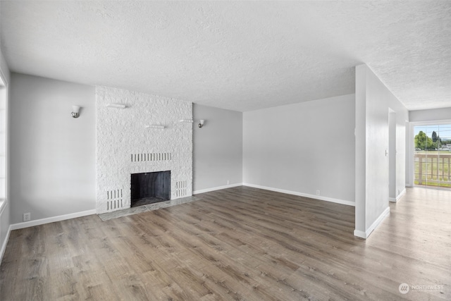 unfurnished living room with a fireplace, hardwood / wood-style floors, and a textured ceiling