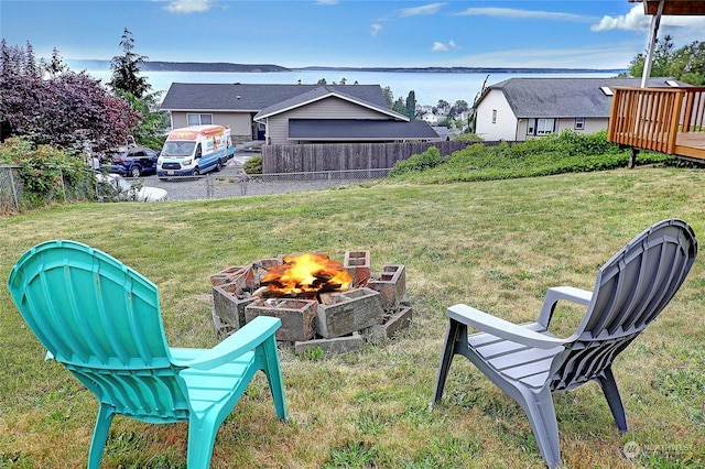 view of yard with a deck with water view and a fire pit