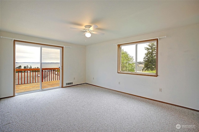 empty room with carpet flooring, ceiling fan, and a healthy amount of sunlight