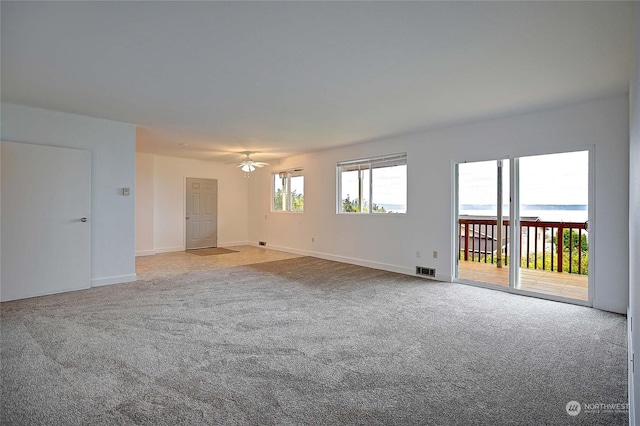 carpeted spare room with ceiling fan and a water view