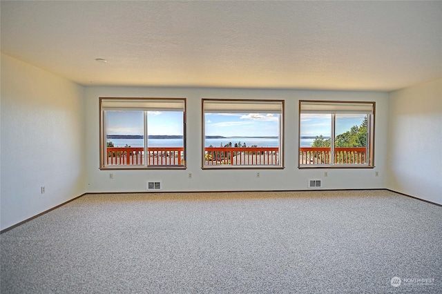 spare room featuring a water view and carpet floors