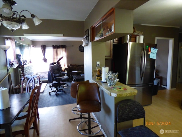 kitchen with kitchen peninsula, stainless steel fridge, and light hardwood / wood-style flooring