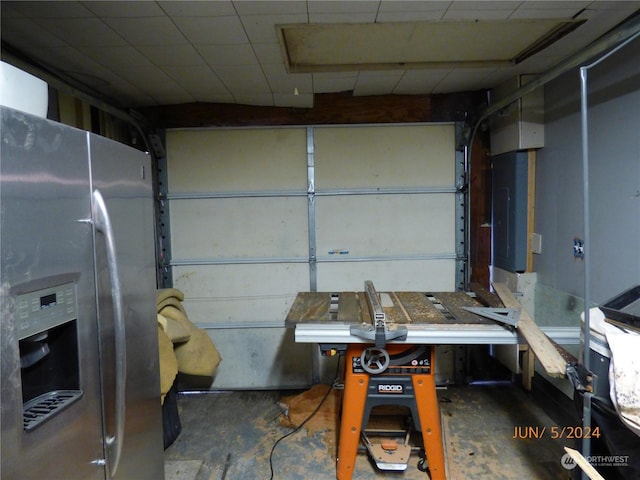 garage featuring stainless steel fridge with ice dispenser and electric panel