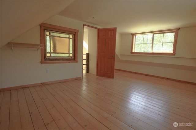 additional living space with light wood-type flooring and vaulted ceiling