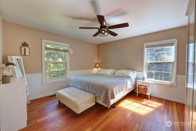 bedroom with hardwood / wood-style flooring, ceiling fan, and multiple windows