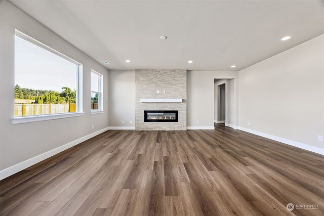 unfurnished living room featuring a stone fireplace and wood-type flooring