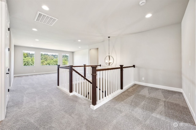 corridor with carpet flooring and an inviting chandelier