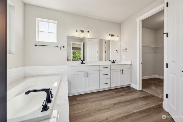 bathroom with tiled tub, vanity, a wealth of natural light, and wood-type flooring