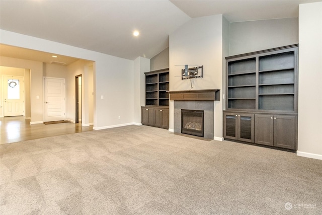 unfurnished living room featuring light carpet, lofted ceiling, and built in features