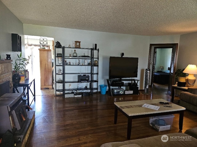 living room featuring a fireplace, dark wood-type flooring, and a textured ceiling