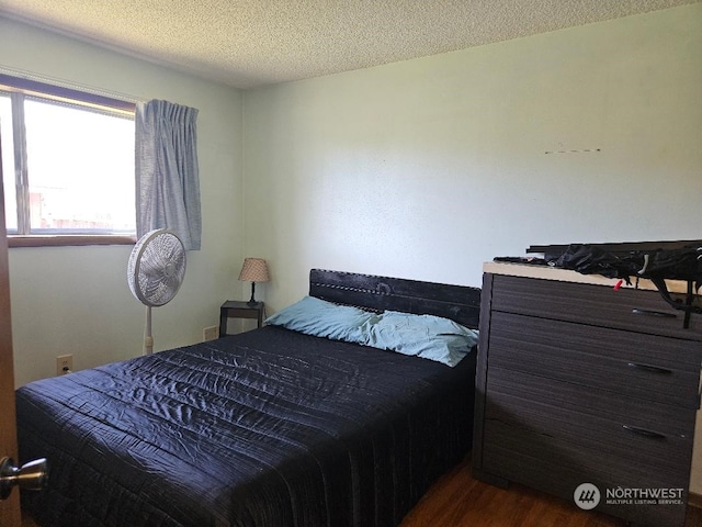 bedroom with a textured ceiling and dark hardwood / wood-style floors