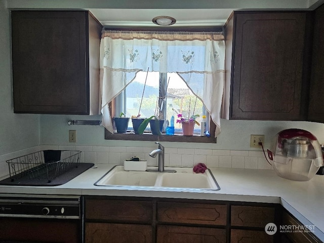 kitchen with black dishwasher, dark brown cabinets, and sink