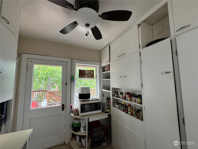 kitchen featuring ceiling fan and white cabinetry