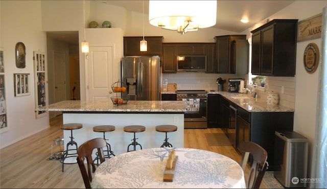 kitchen featuring decorative backsplash, a center island, stainless steel appliances, and hanging light fixtures