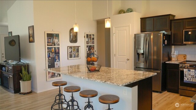 kitchen featuring light stone countertops, appliances with stainless steel finishes, backsplash, and a center island