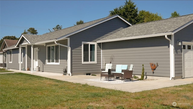 rear view of property featuring a yard, a garage, and a patio area