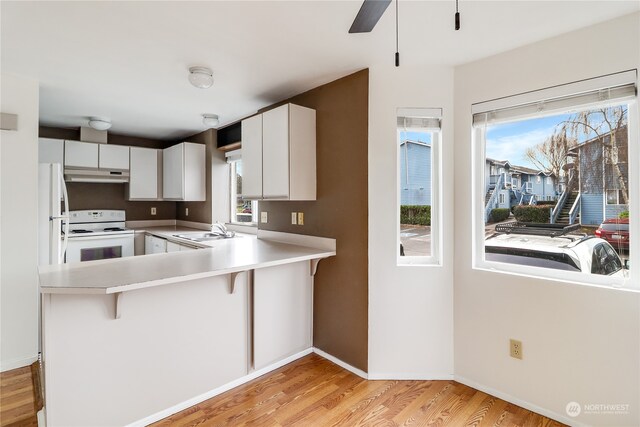 kitchen featuring white cabinetry, a breakfast bar area, light wood-type flooring, and kitchen peninsula