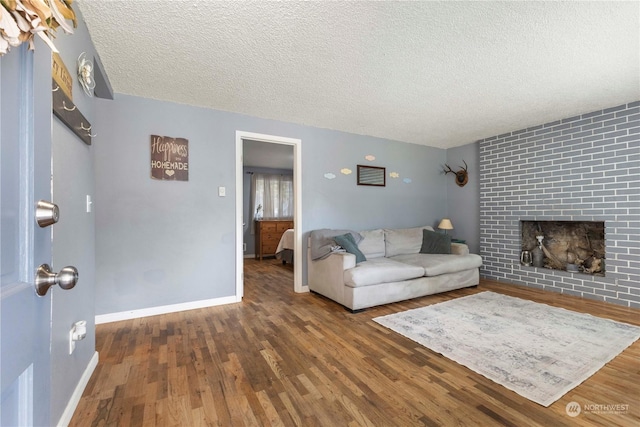 living room with dark hardwood / wood-style floors, a textured ceiling, and a fireplace