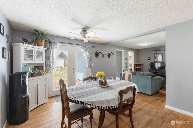 dining room featuring ceiling fan, light wood-type flooring, a textured ceiling, and french doors