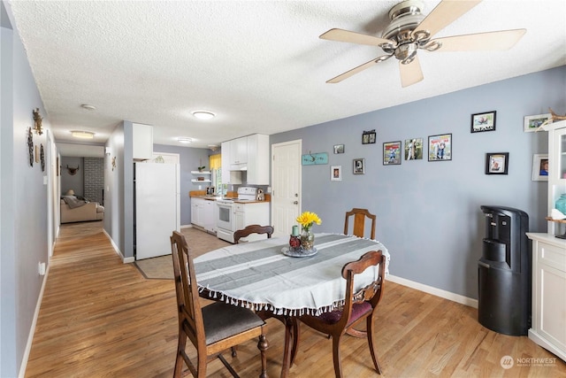 dining room with a textured ceiling, light hardwood / wood-style flooring, and ceiling fan