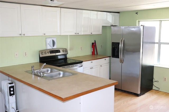 kitchen with appliances with stainless steel finishes, white cabinetry, sink, light hardwood / wood-style floors, and kitchen peninsula