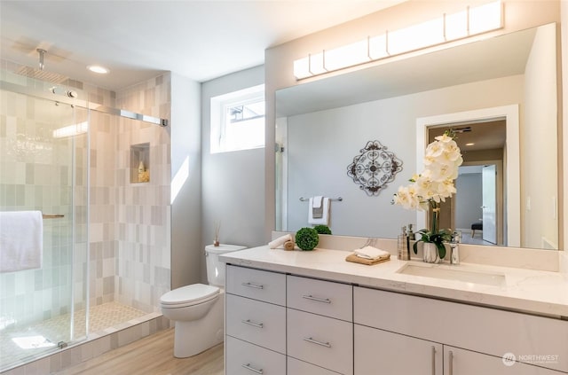 bathroom with hardwood / wood-style floors, vanity, toilet, and walk in shower