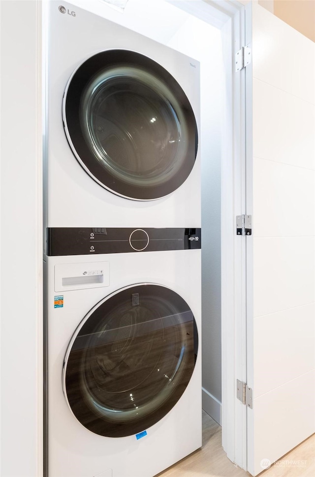 laundry area with stacked washer and dryer and light hardwood / wood-style floors