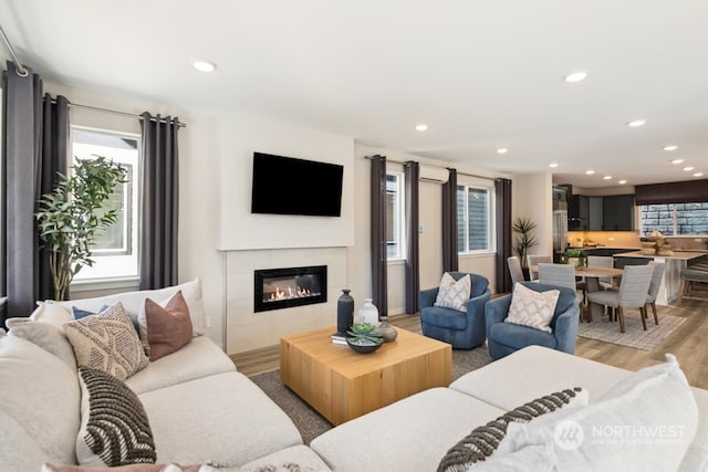 living room featuring a healthy amount of sunlight, a tiled fireplace, and light hardwood / wood-style floors