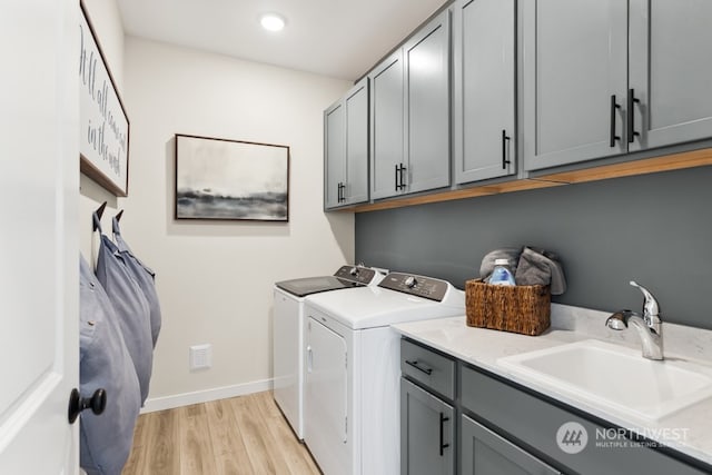 washroom with sink, light hardwood / wood-style floors, cabinets, and washing machine and clothes dryer