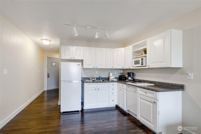 kitchen featuring a sink, white appliances, dark countertops, and dark wood finished floors