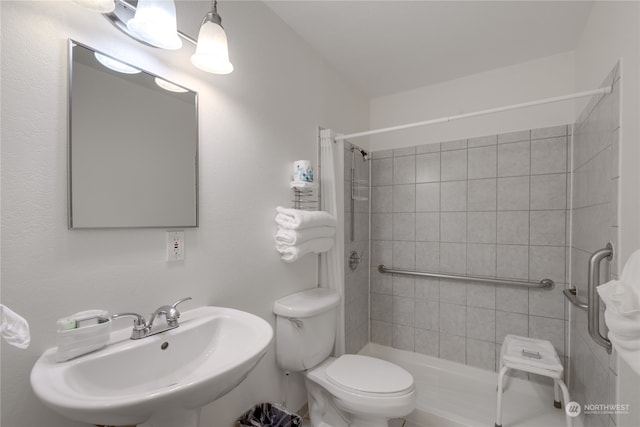 bathroom featuring tiled shower, toilet, and sink