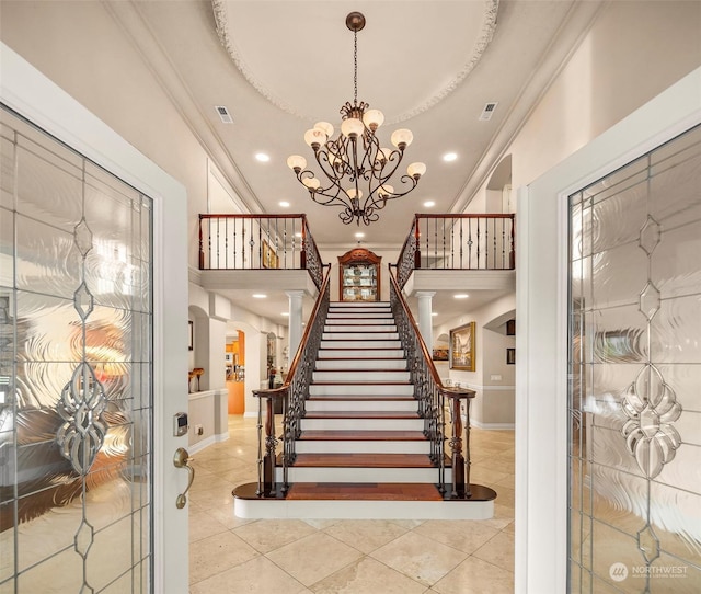 tiled foyer featuring crown molding and an inviting chandelier