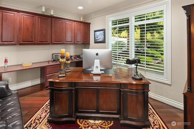 office space featuring built in desk, dark wood-type flooring, and ornamental molding