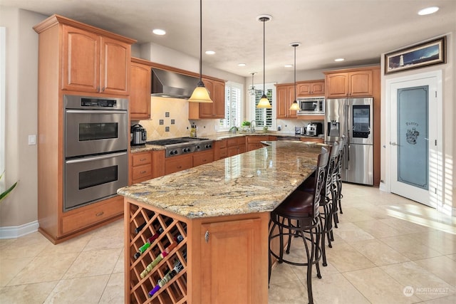 kitchen featuring a center island, a kitchen breakfast bar, wall chimney range hood, hanging light fixtures, and appliances with stainless steel finishes