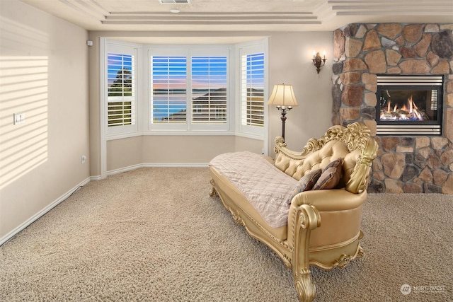 living area featuring a stone fireplace and carpet floors